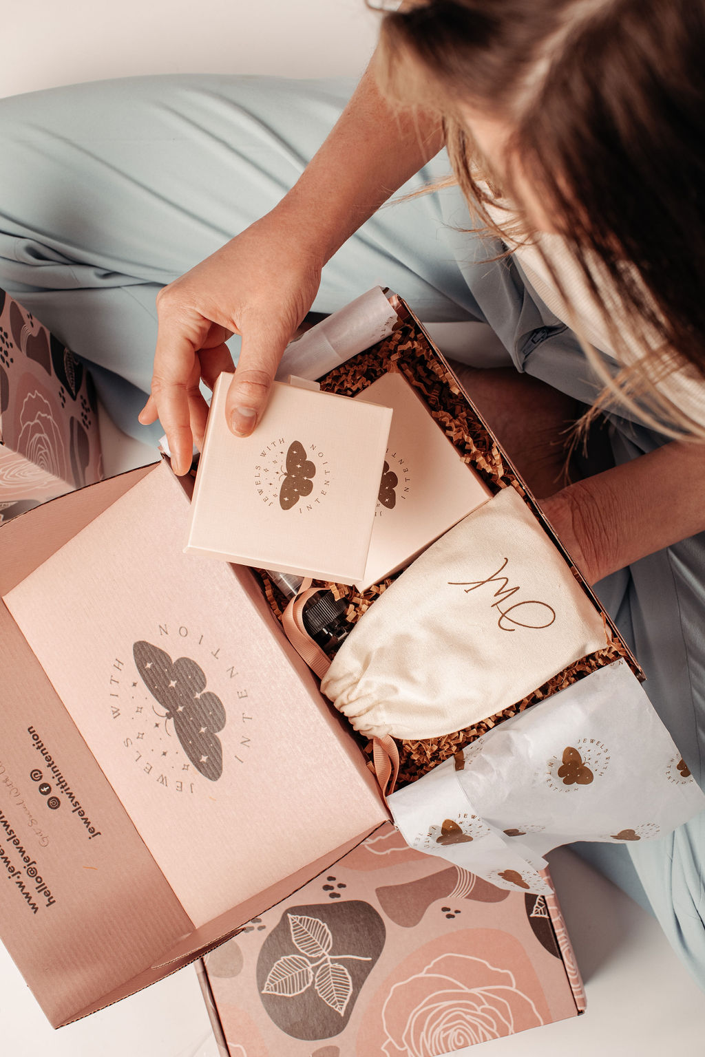 A Jewels With Intention monthly box being unboxed, showing the keepsake jewelry box, dust bag, and tissue